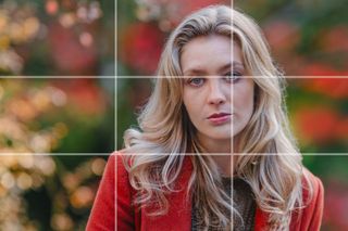 Rule of thirds grid overlaid onto portrait of woman wearing red coat against a blurred red, green and gold background