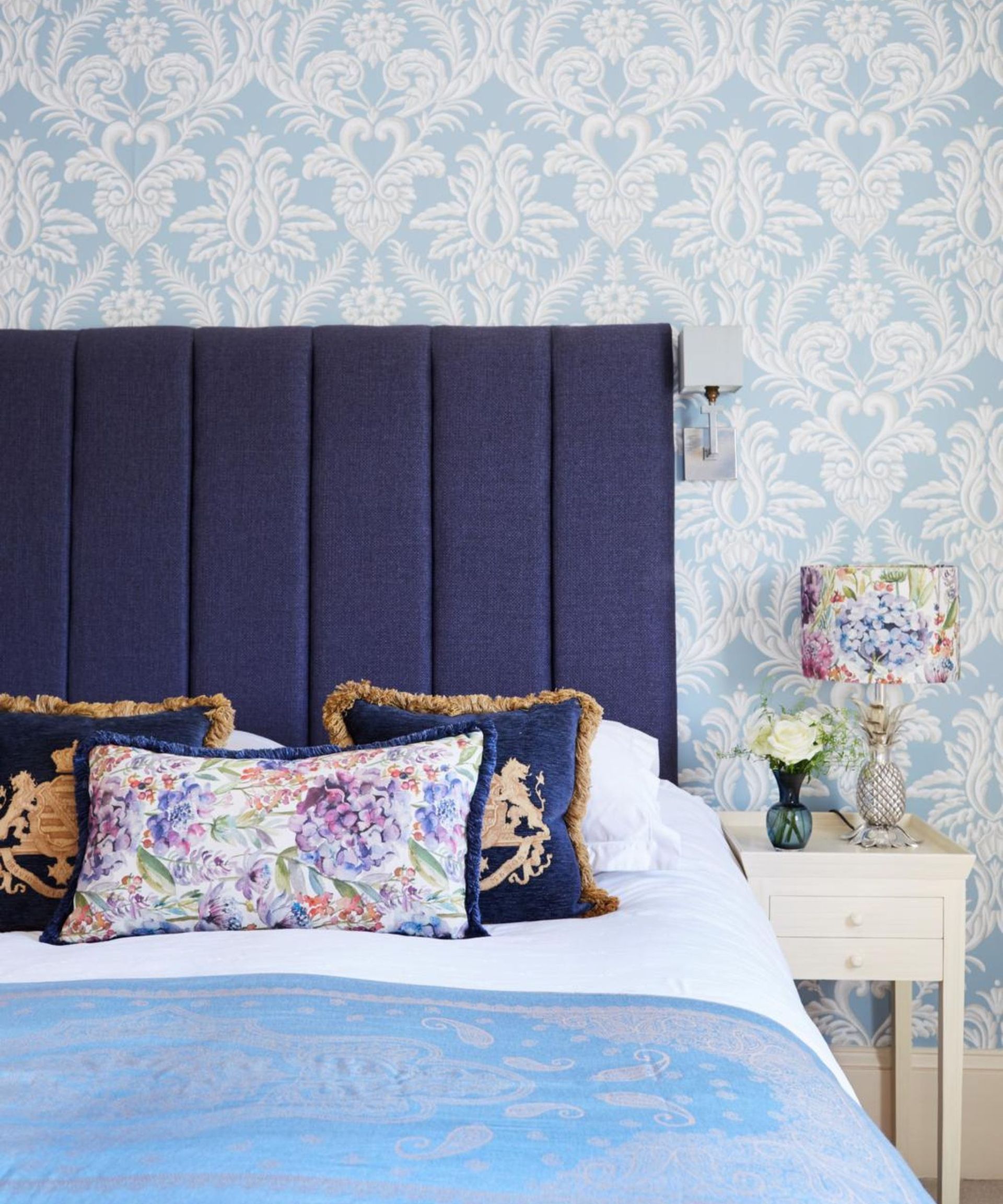 Blue pillows on a bed against blue wallpaper.