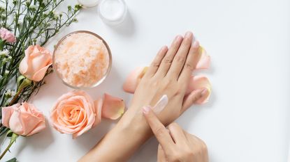 close up of swatch of moisturizer on hands surrounded by flowers