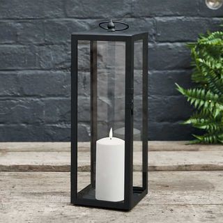 Black metal outdoor lantern with LED candle to show the quiet luxury garden trend