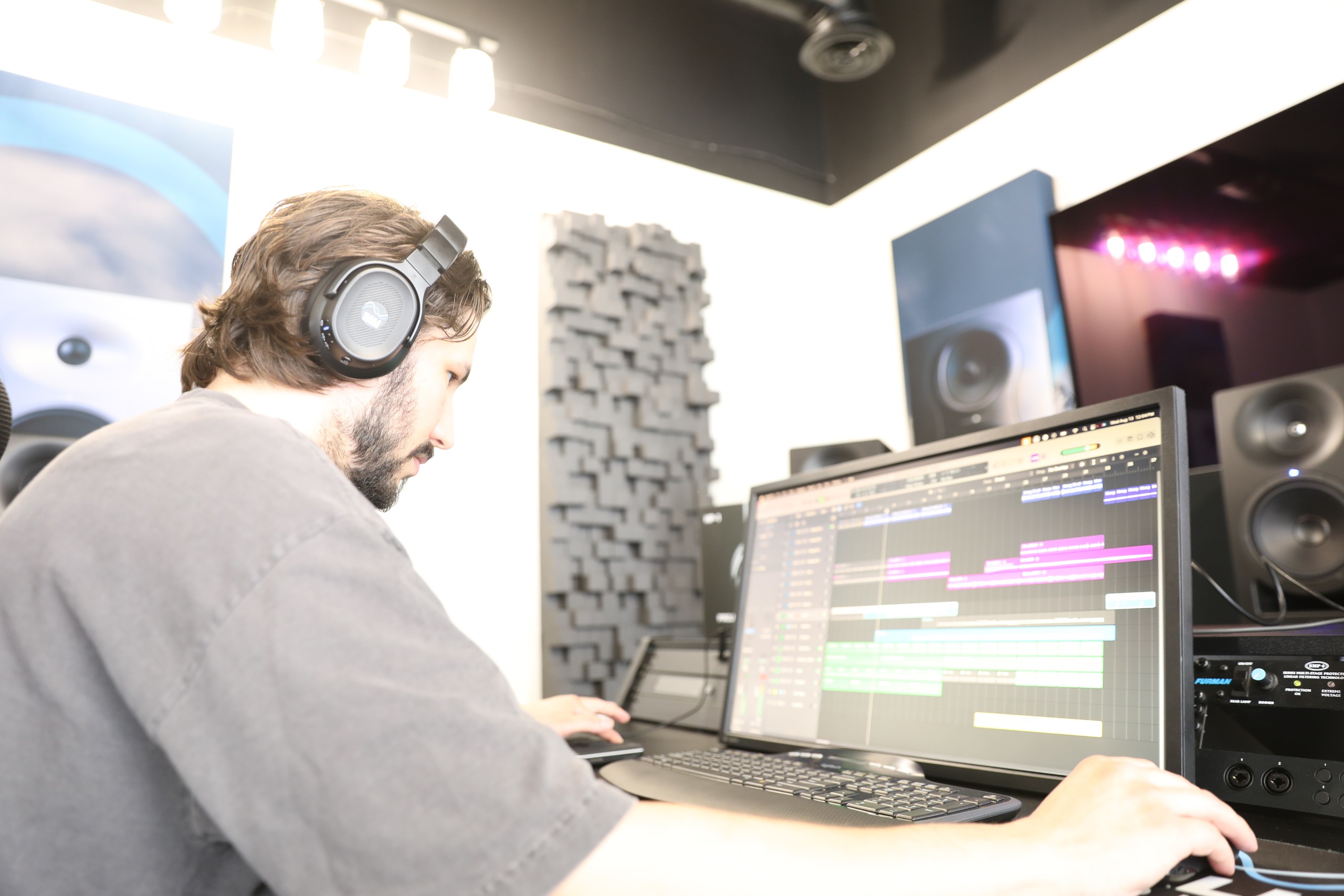 A man using a PC, wearing Kali Audio HP-1 studio headphones