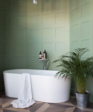 A green bathroom by best bathroom designer Ripples with white bath tub and pot plant.