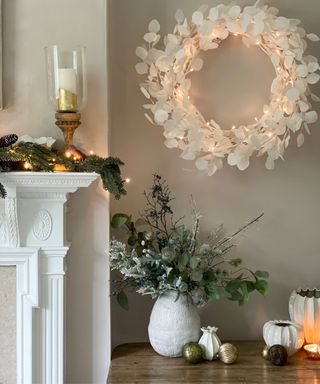 A minimalist Christmas living room with a white fireplace, a Christmas wreath, and decor on a table