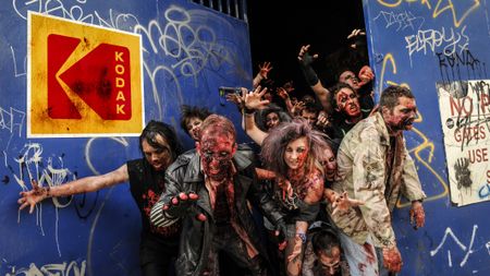 Zombies breaking out of blue gates with a Kodak logo on them