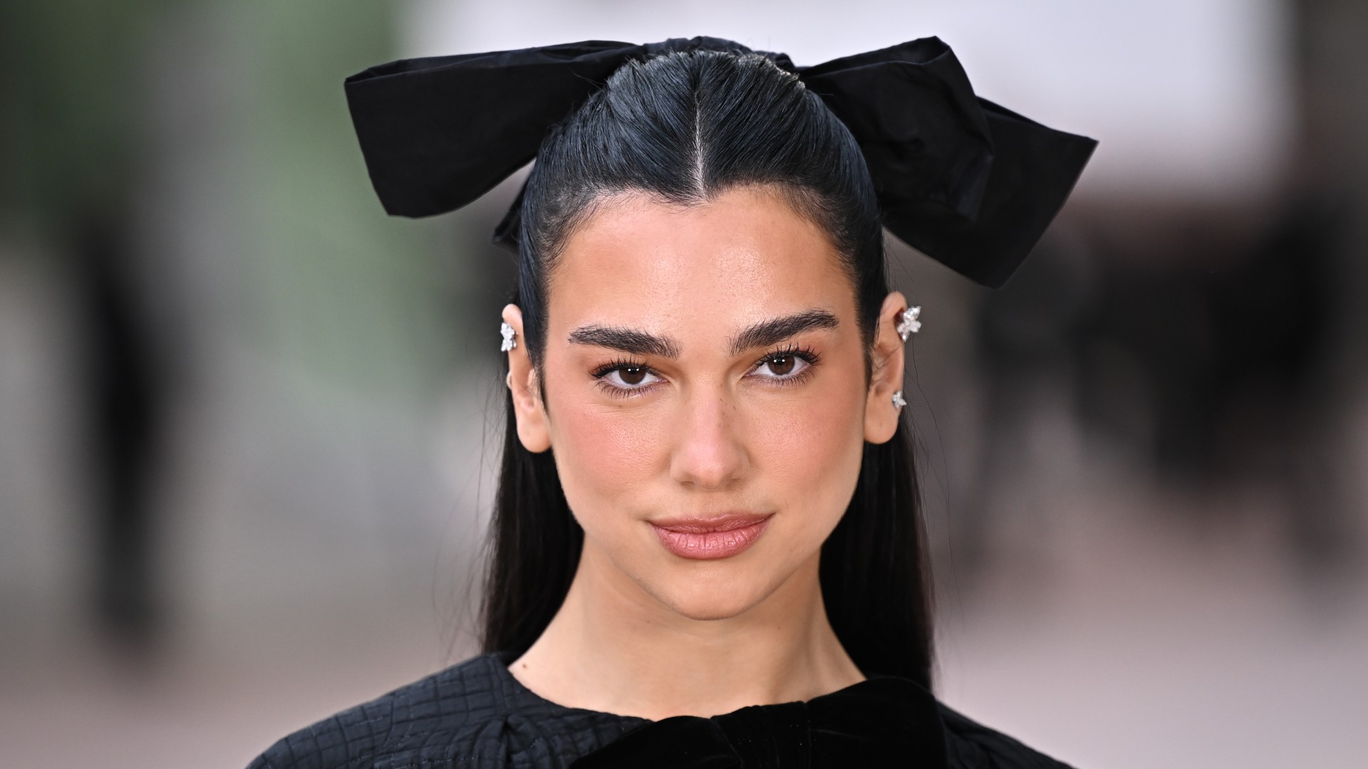 a woman with black hair wearing a large black hair bow