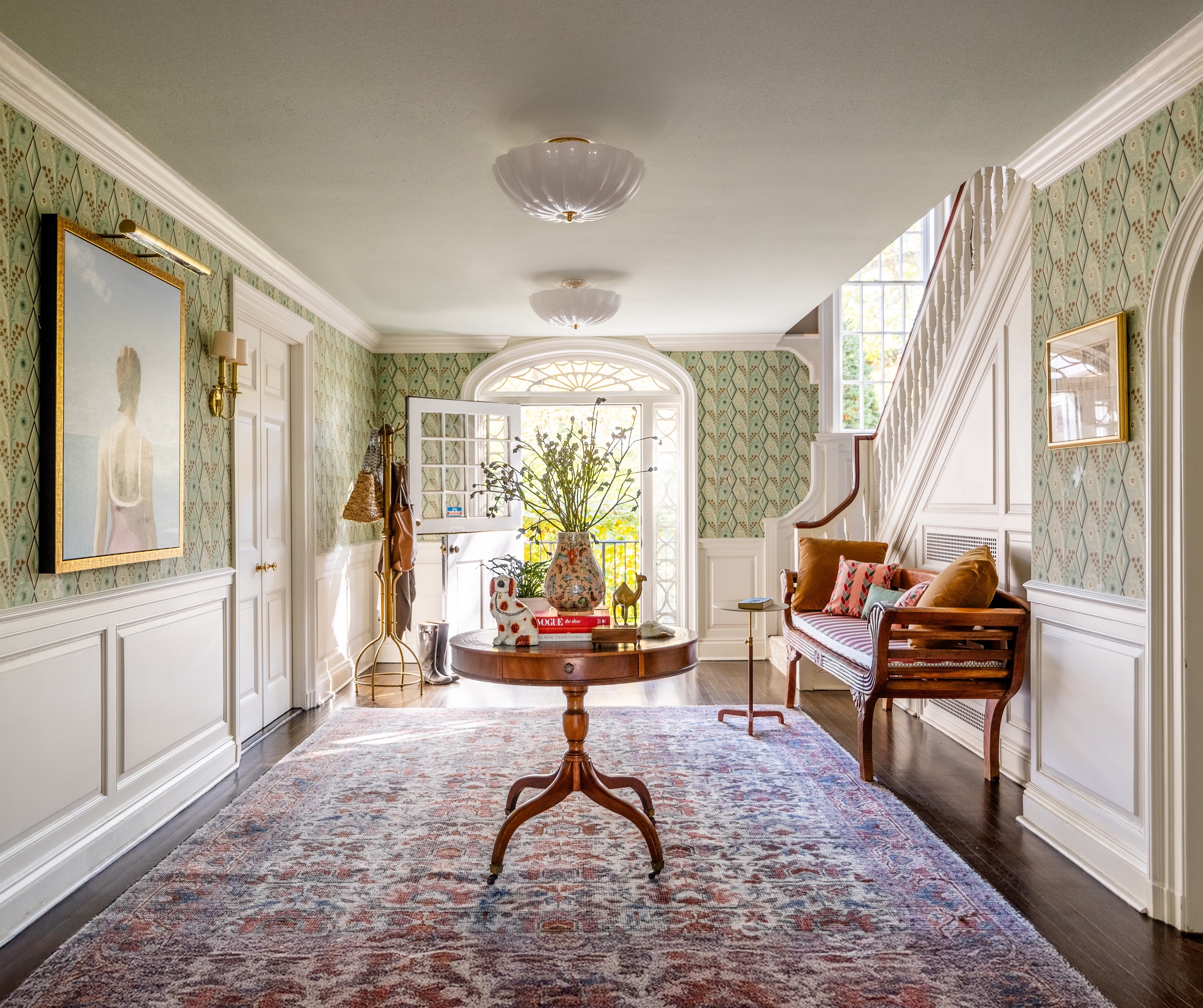 Opulent entryway with wallpaper, round console table and oversized art