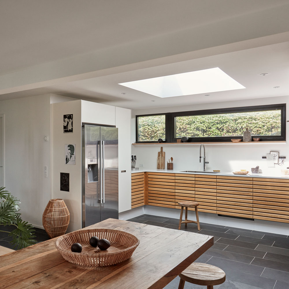 Glass kitchen extension with wooden counter, dining table and chairs