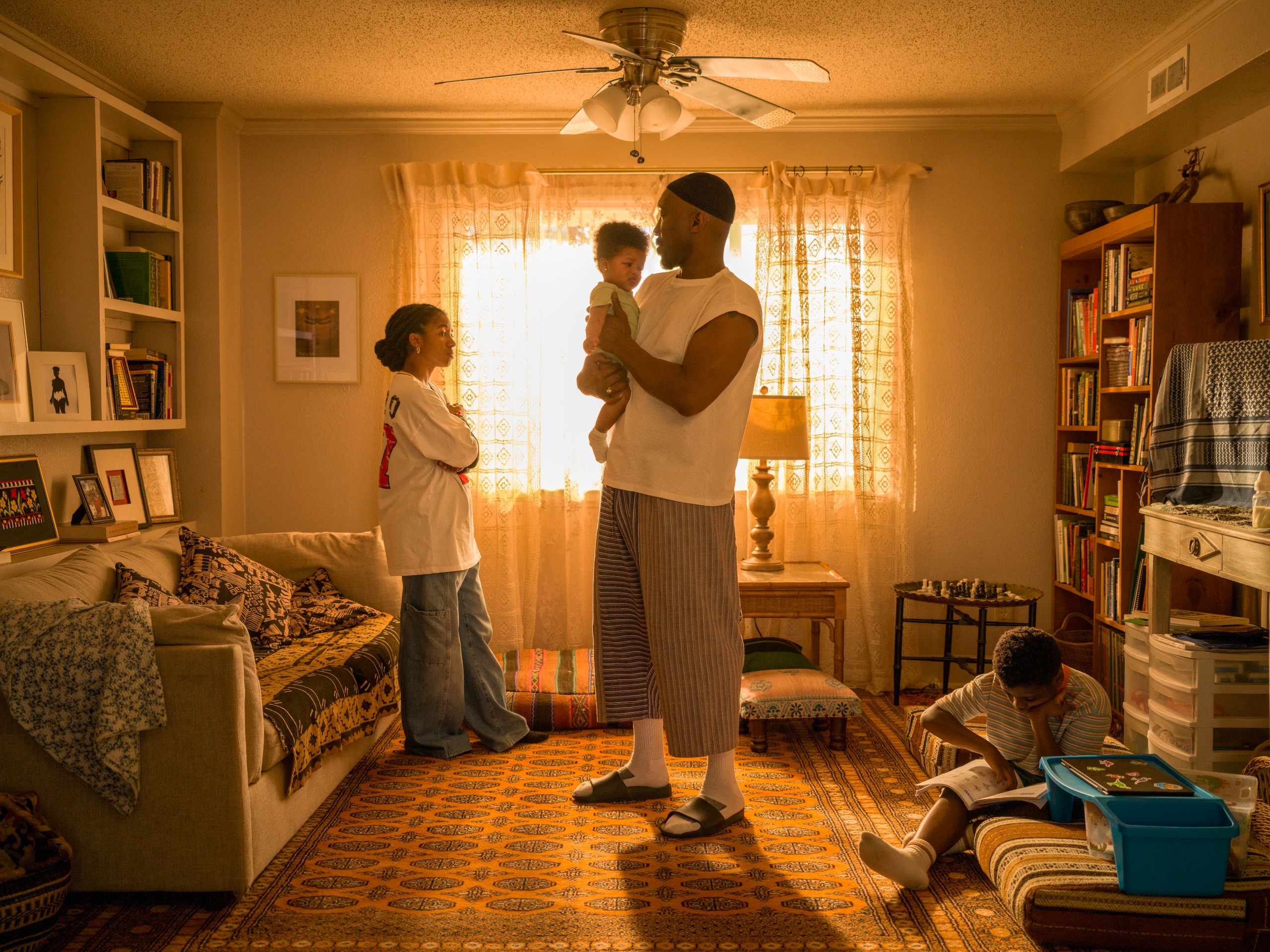 Adia as Fatiha stands with her arms crossed by a window. Mahershala Ali as Latif stands while holding an infant. Jahleel Kamara&amp;nbsp;as Qadir sits on the floor reading in your mother your mother you mother
