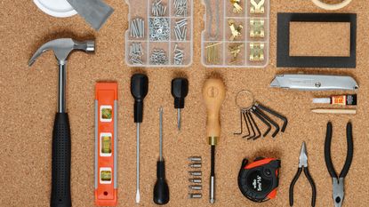 Overhead shot of household tools laid out on a cork surface