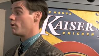 Jim Carrey is pushed next to a sign for Kaiser Chicken.