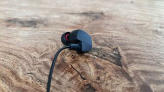 The Final VR3000 gaming earbuds placed on a wooden surface.