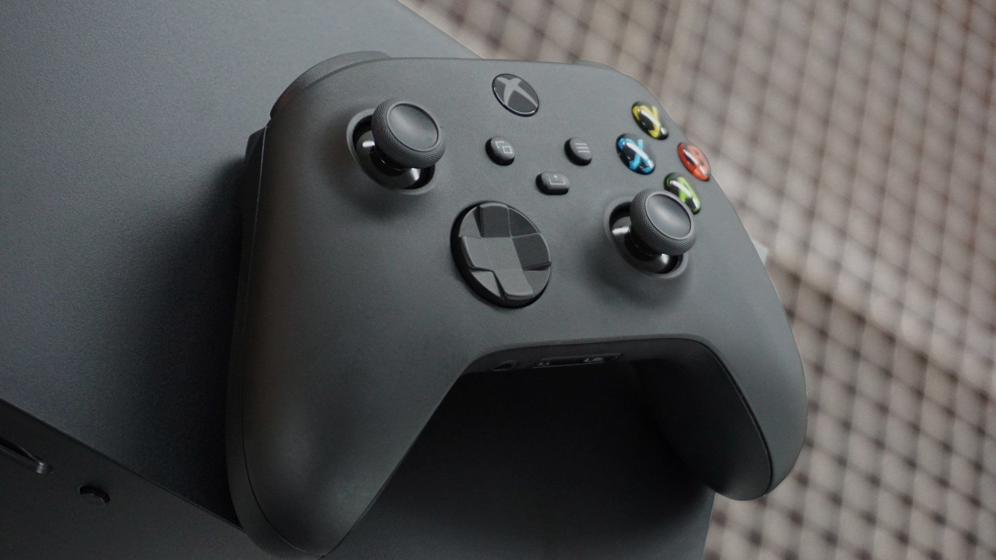 Um Xbox Wireless Controller preto em cima de um Xbox Series X.