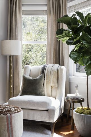 accent chair in window with throw, pillow and plant