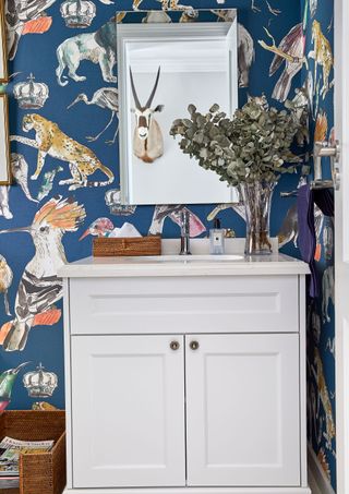 Blue wallpaper with animal prints, white cabinet