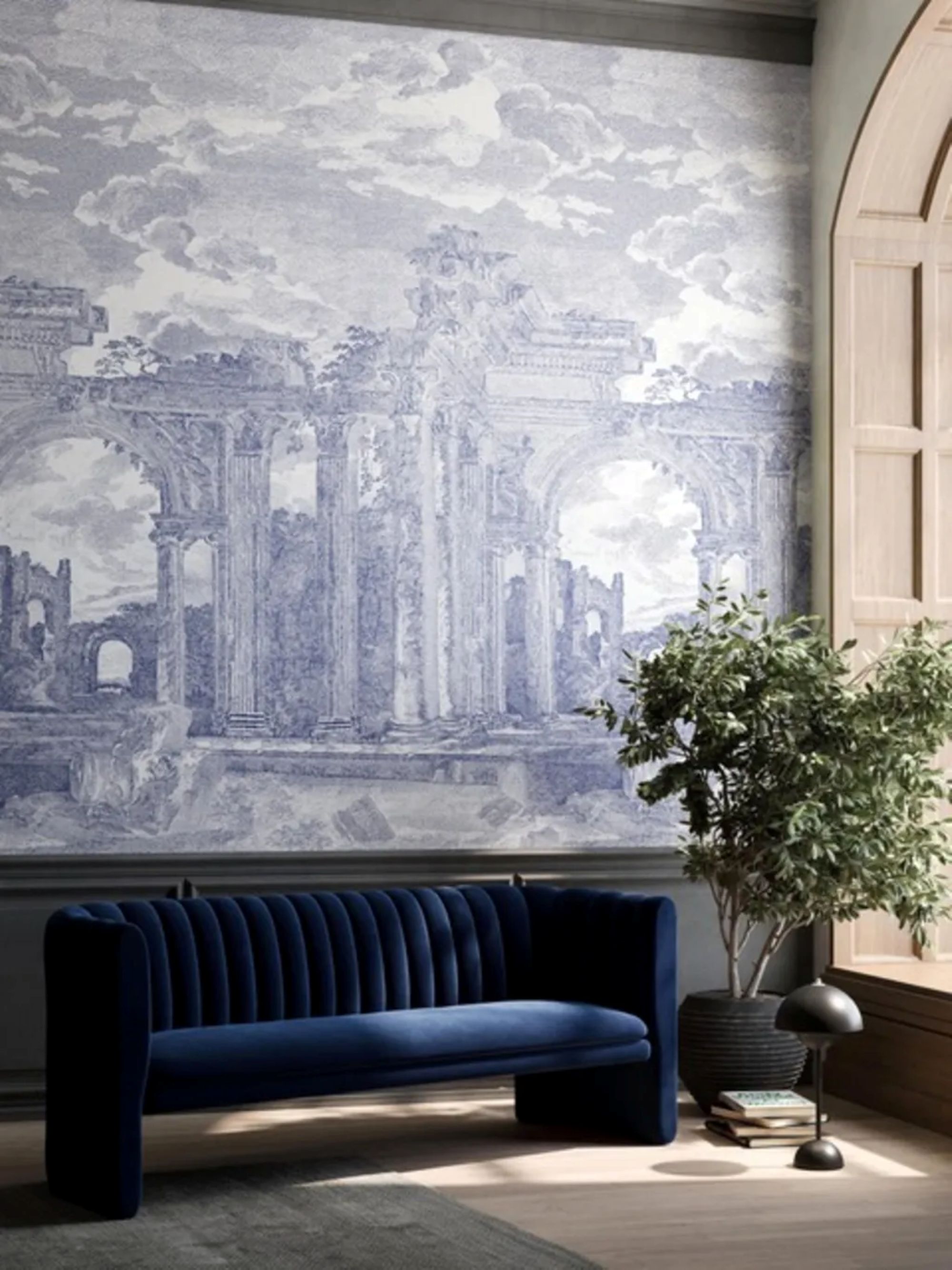 a midnight blue sofa in a room with a large mural on the wall and a potted plant