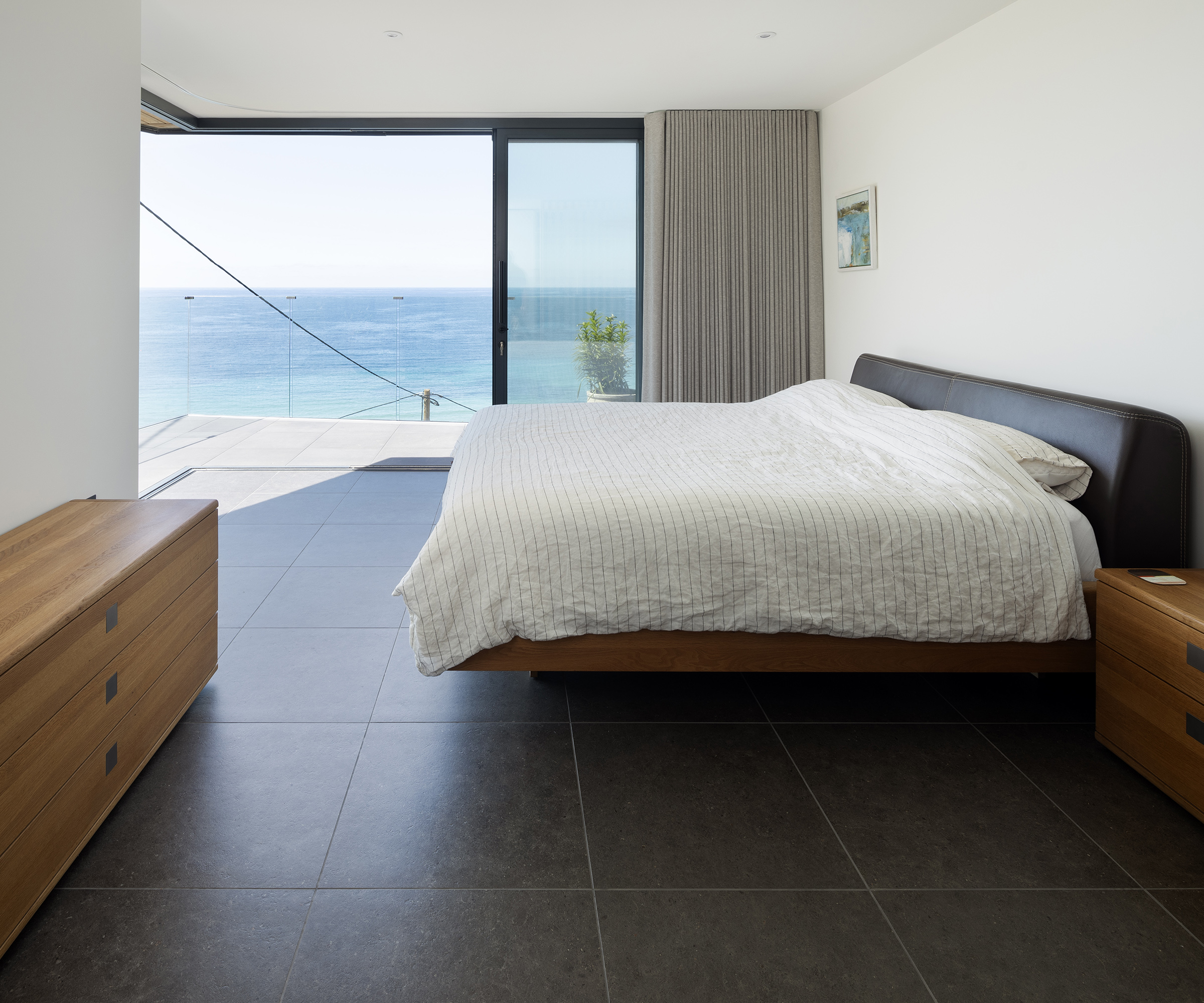 Bedroom with cantilever glass sliding doors which open out onto a private terrace with a sea view