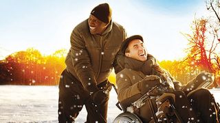 Driss skjuter på Philippe som sitter i sin rullstol under en promenad en solig vinterdag. De två skrattar och ser glada ut.
