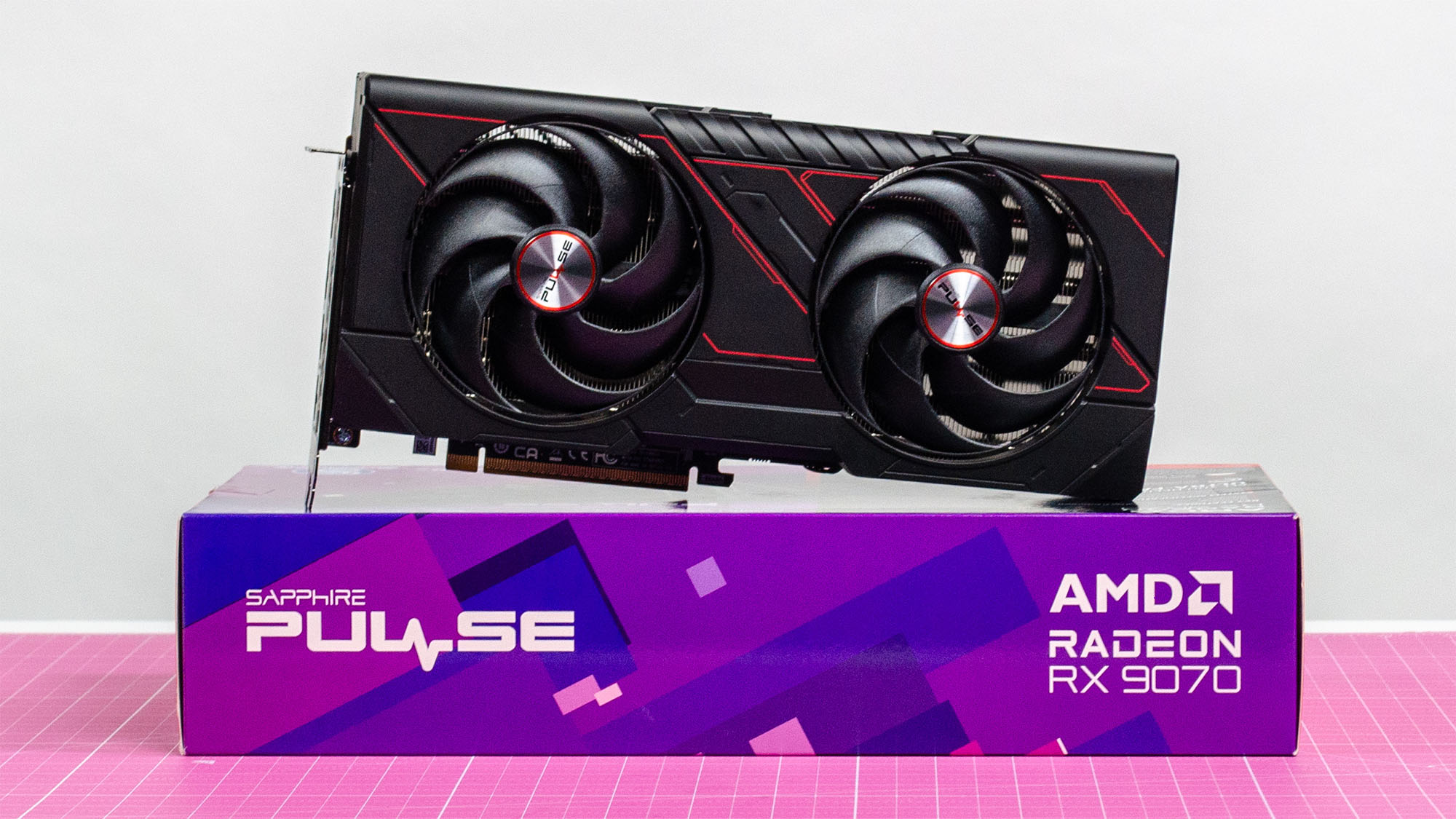 An AMD Radeon RX 9070 sitting on its retail packaging with its fans visible