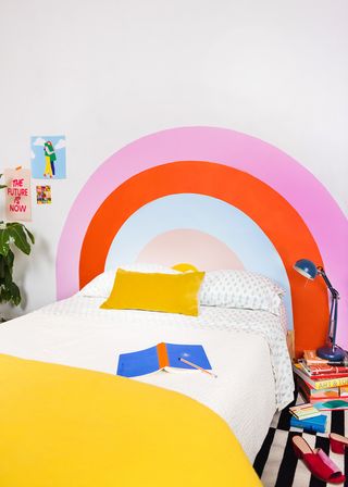 Kids' room paint ideas with rainbow painted headboard in a white scheme with colorful accessories.