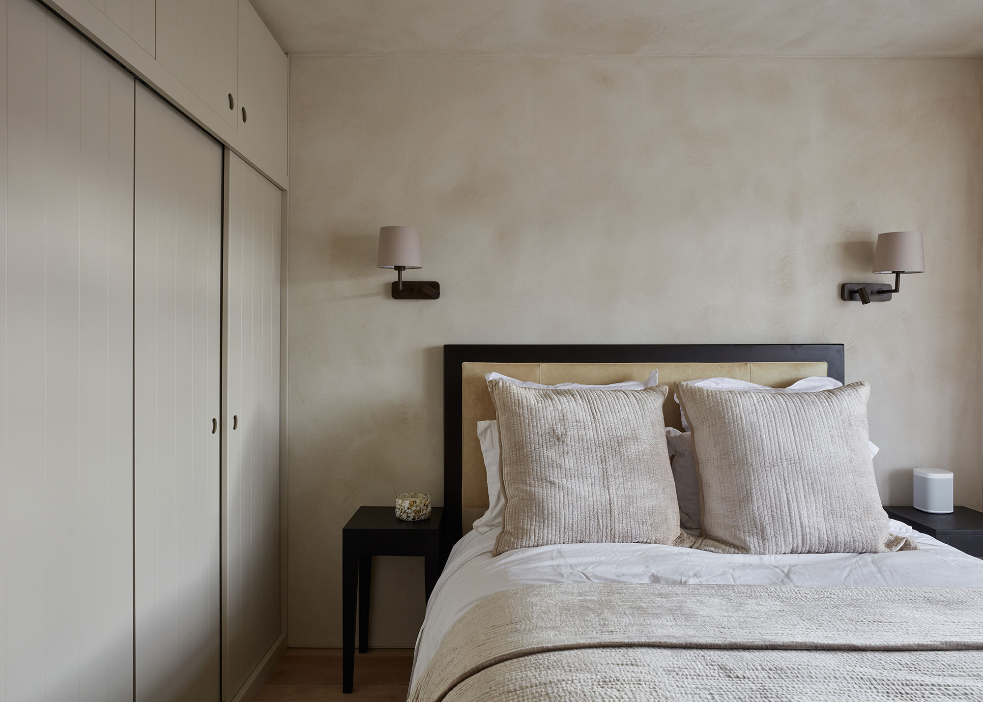 bedroom with bare plaster walls and fitted sliding wardrobes