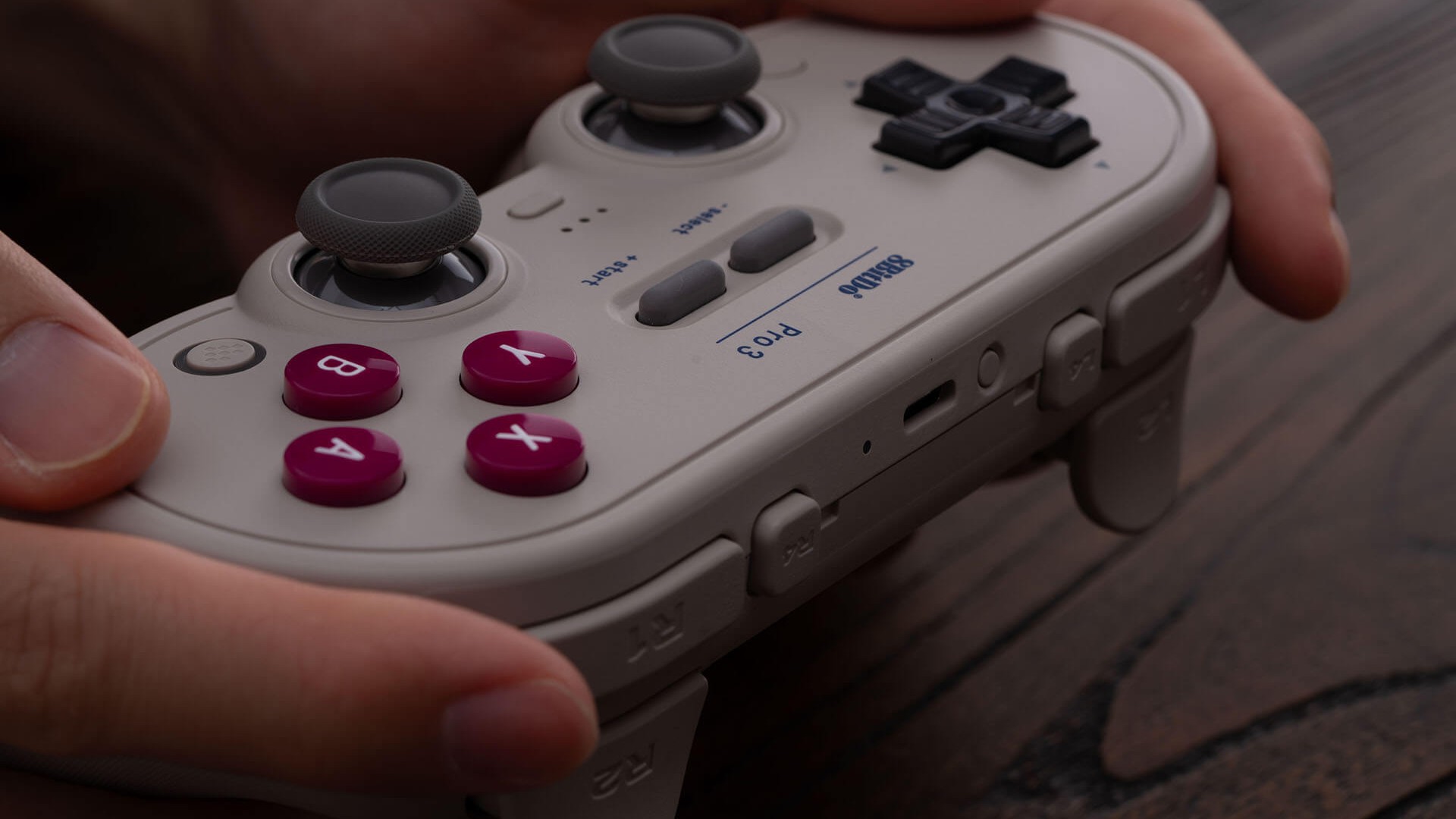 A beige 8BitDo Pro 3 controller in a player&#039;s hands