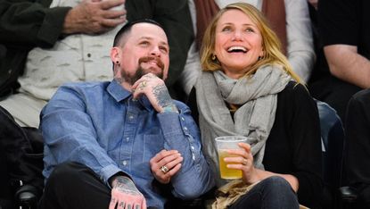 Benji Madden and Cameron Diaz smiling at a basketball game.