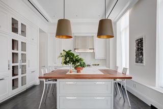 white kitchen with chrome hardware and gold lined island pendants