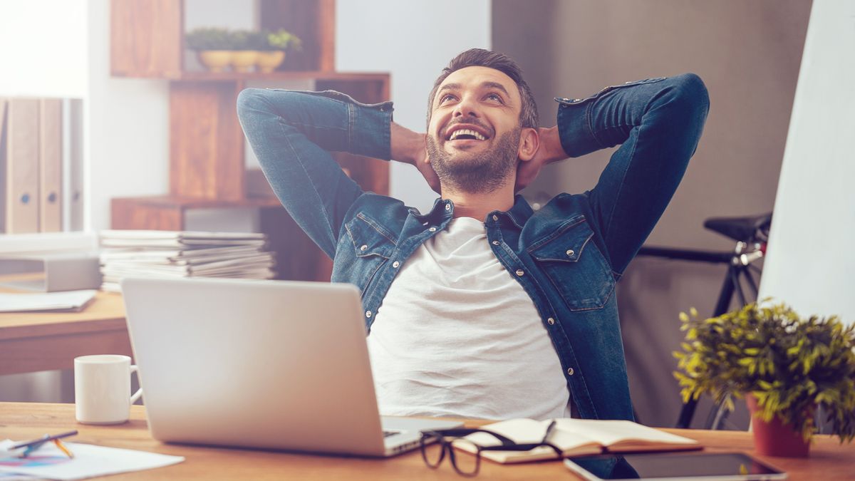 A man sitting in front of a laptop with an expression of joy on his face.