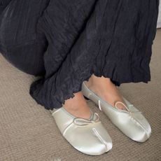 a woman wearing a pair of satin tabi flats and black pants