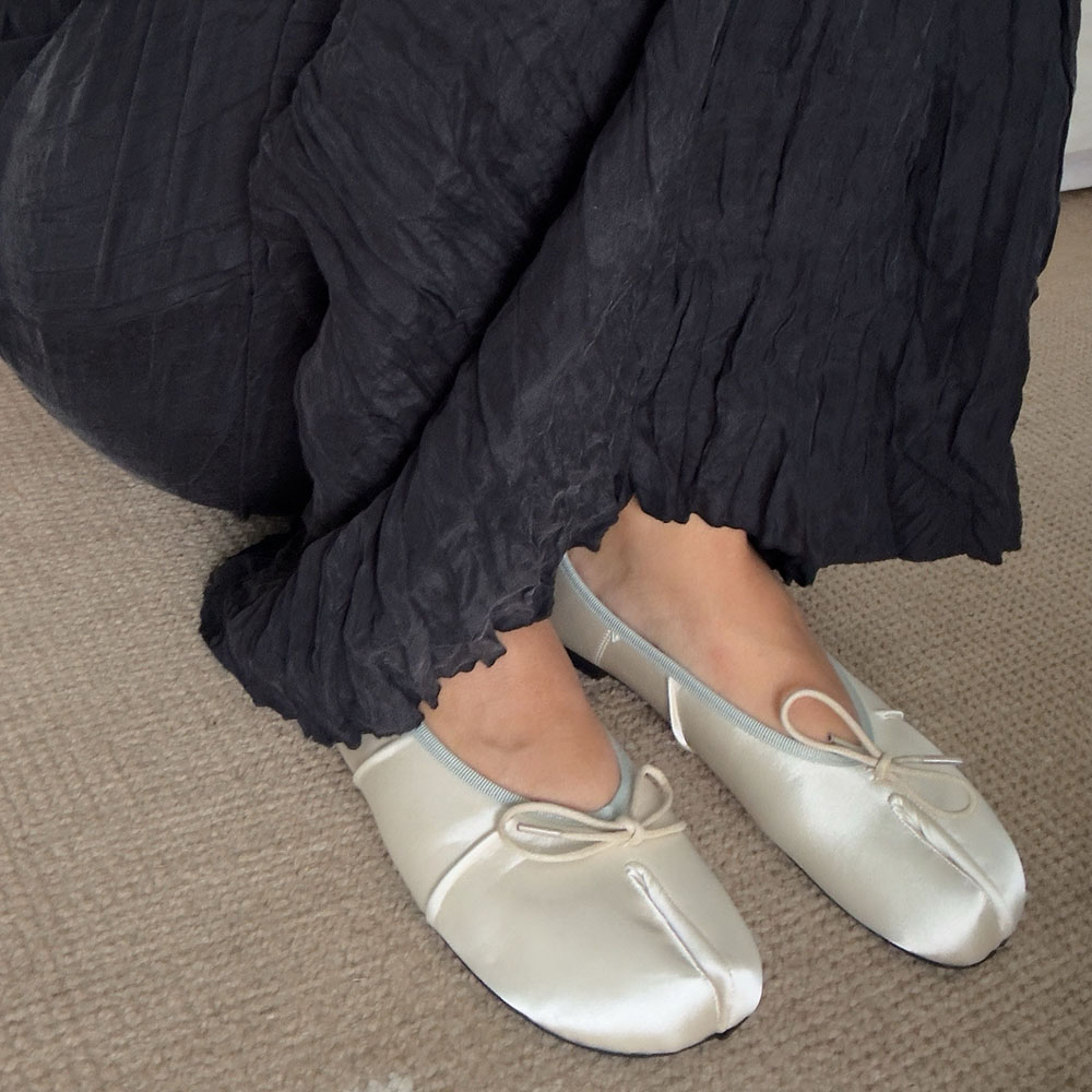 a woman wearing a pair of satin tabi flats and black pants