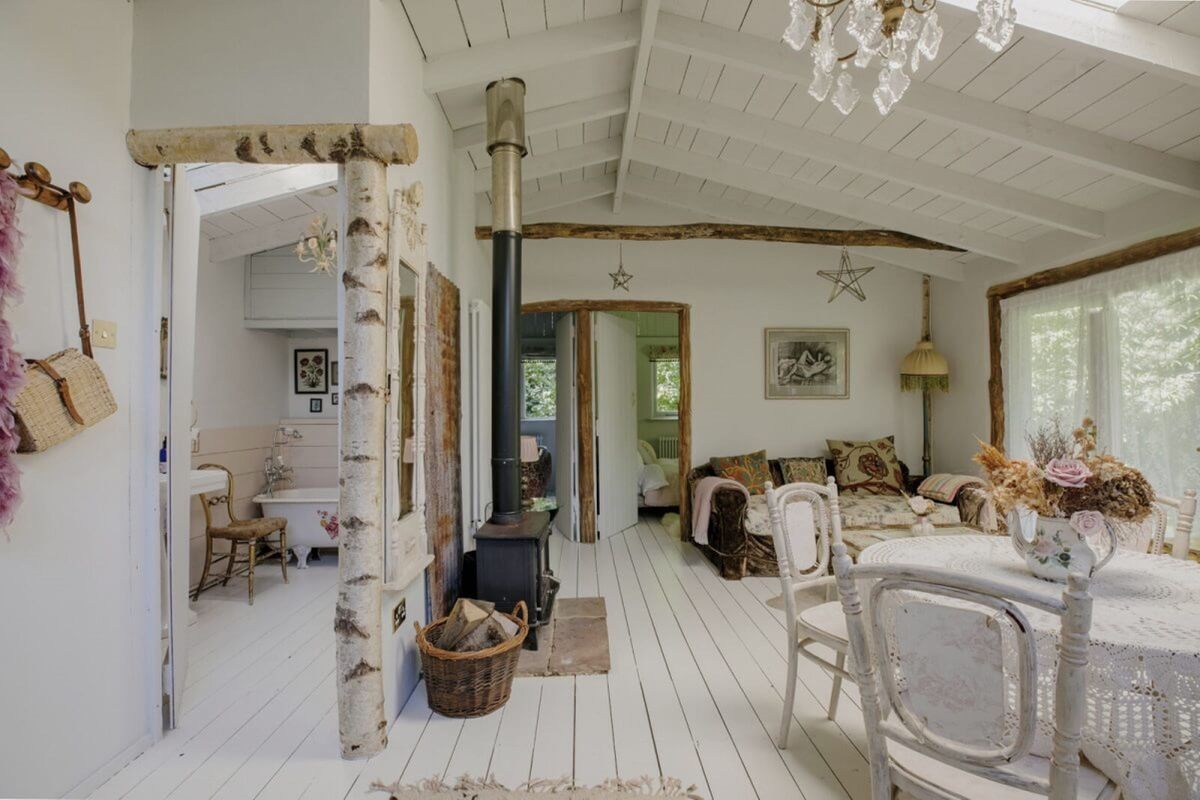 A living room in a cabin with silver birch logs decorating it and housing a bathroom and two bedrooms