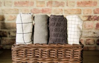 An array of patterned white and grey and navy tea towels arranged in a storage basket.