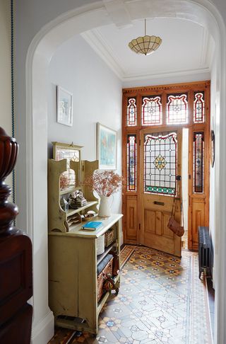 Victorian hallway featuring original encaustic tiled floor and front door with stained glass