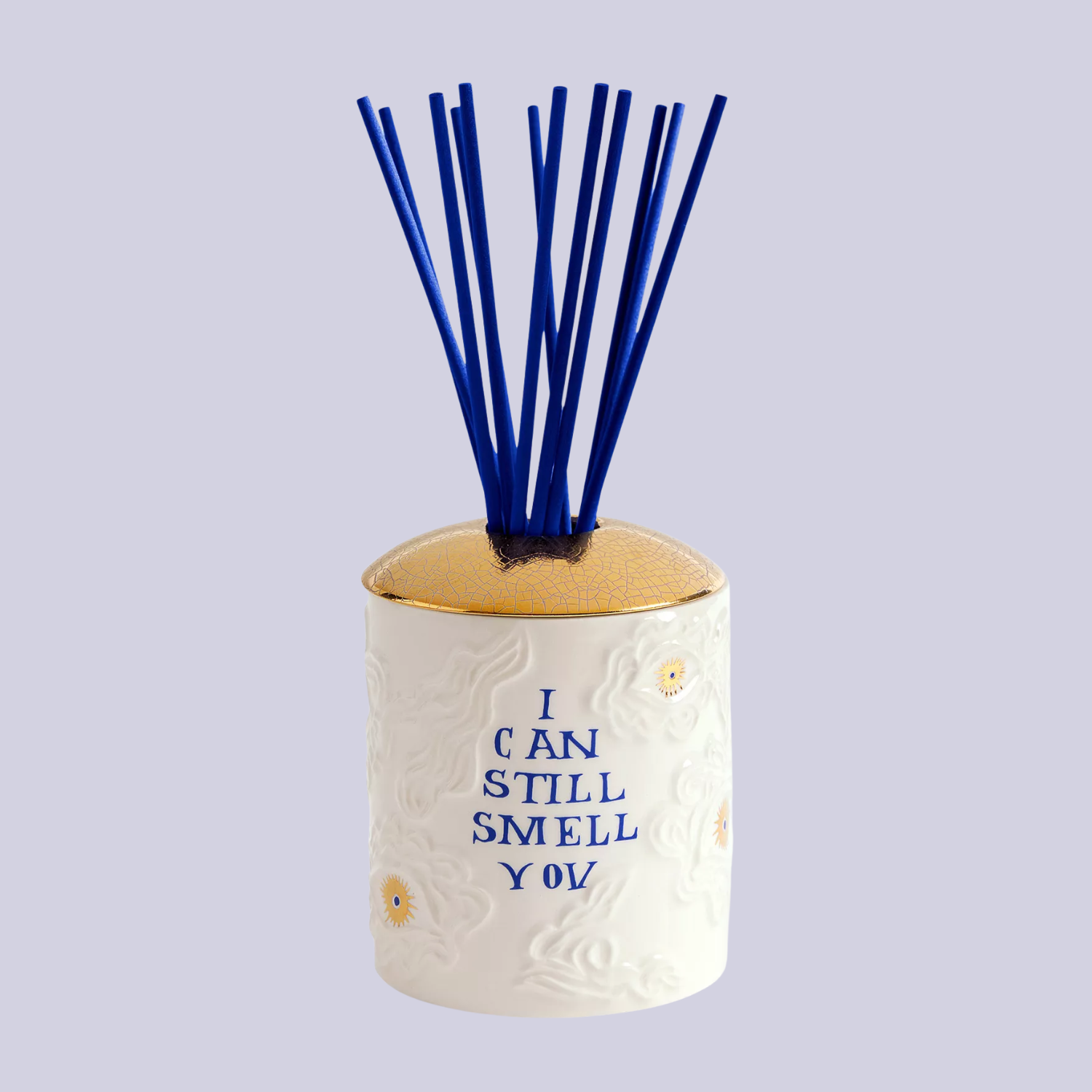 A white ceramic reed diffuser with a gold lid and blue reeds