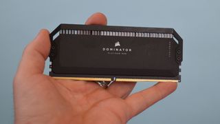 A man's hand holding a stick of Corsair Dominator Platinum RGB DDR5 RAM