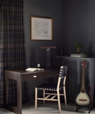 corner of bedroom with dark gray walls, desk and chair and guitar