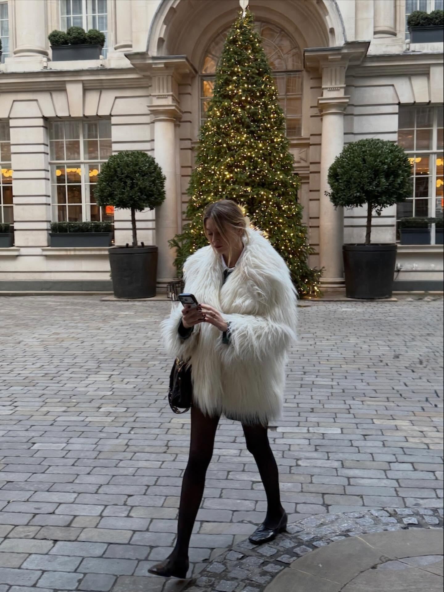 @camillecharriere wearing a furry coat, tights, and high-vamp pumps.