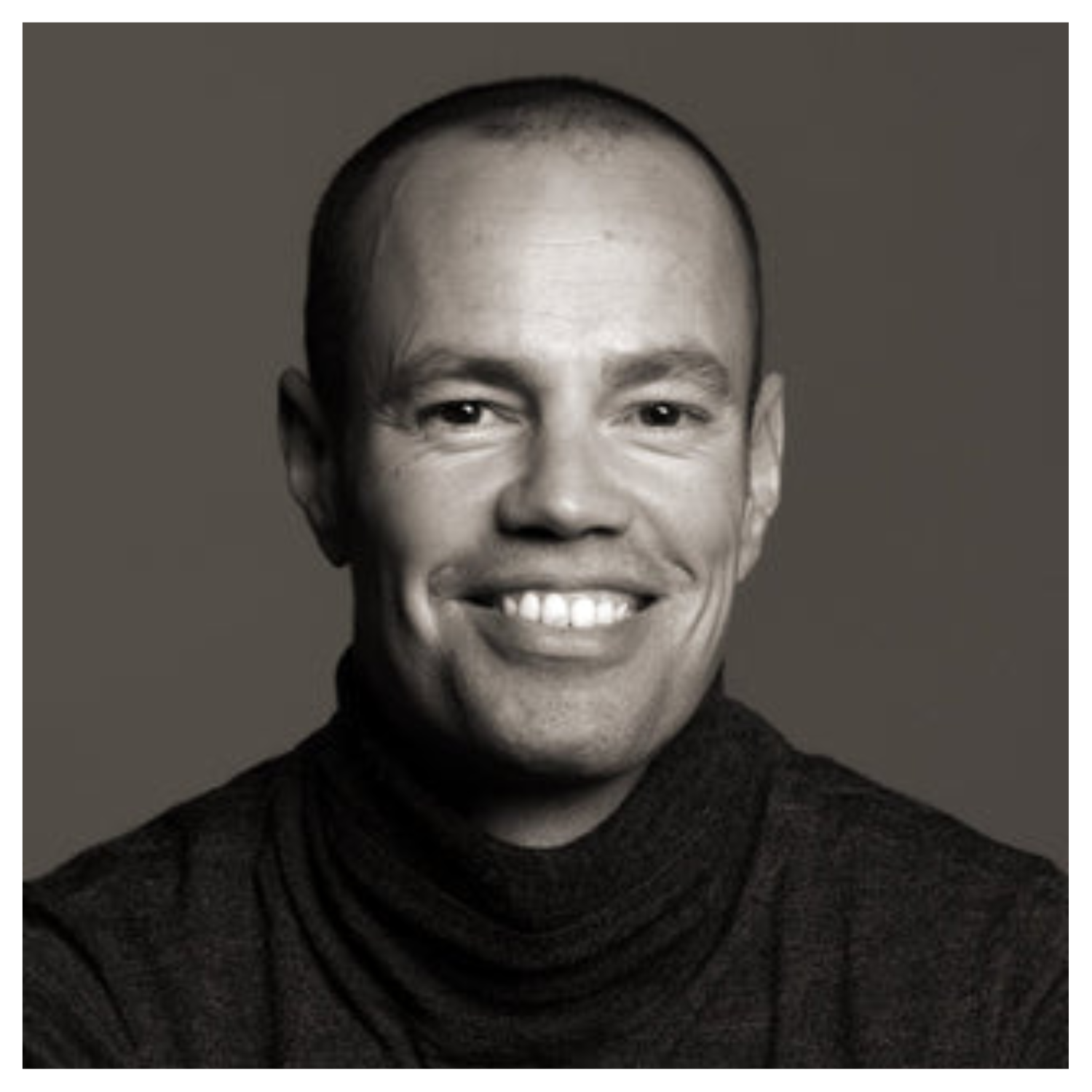 A smiling man in a black turtleneck