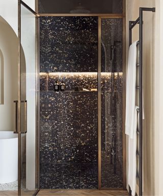 Bronze framed glass shower doors, textured stone walls and floor