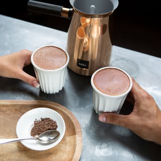 Hotel Chocolat Velvetiser on countertop next to two mugs filled wit hot chocolate
