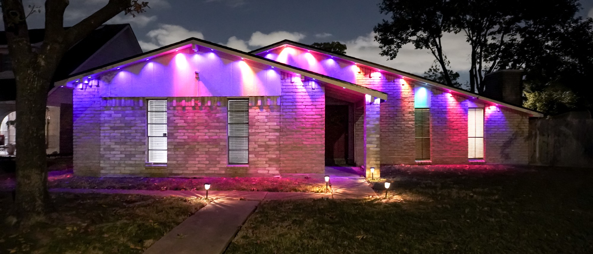 A wide shot showing the Govee Permanent Outdoor Lights Prism installed on a home's roof with their tri-color lighting effects in full display