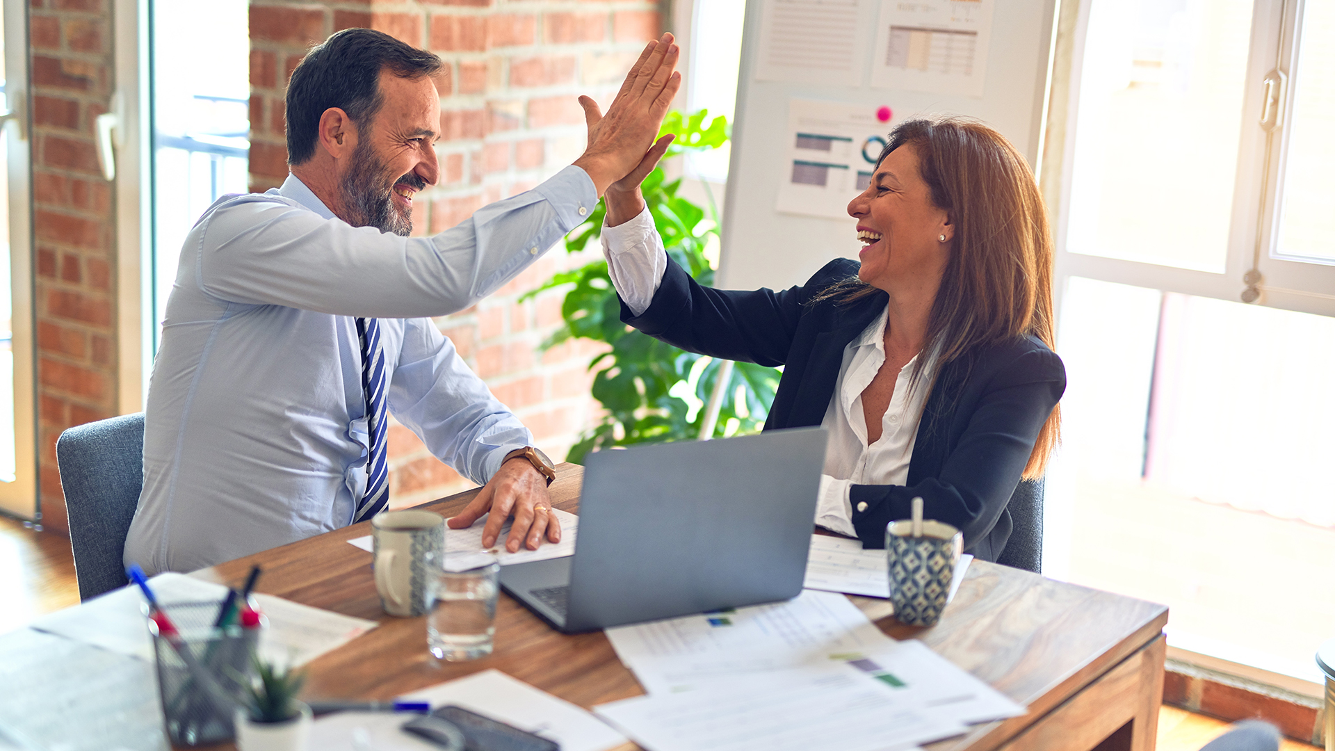 man and woman high fiving in a business meeting