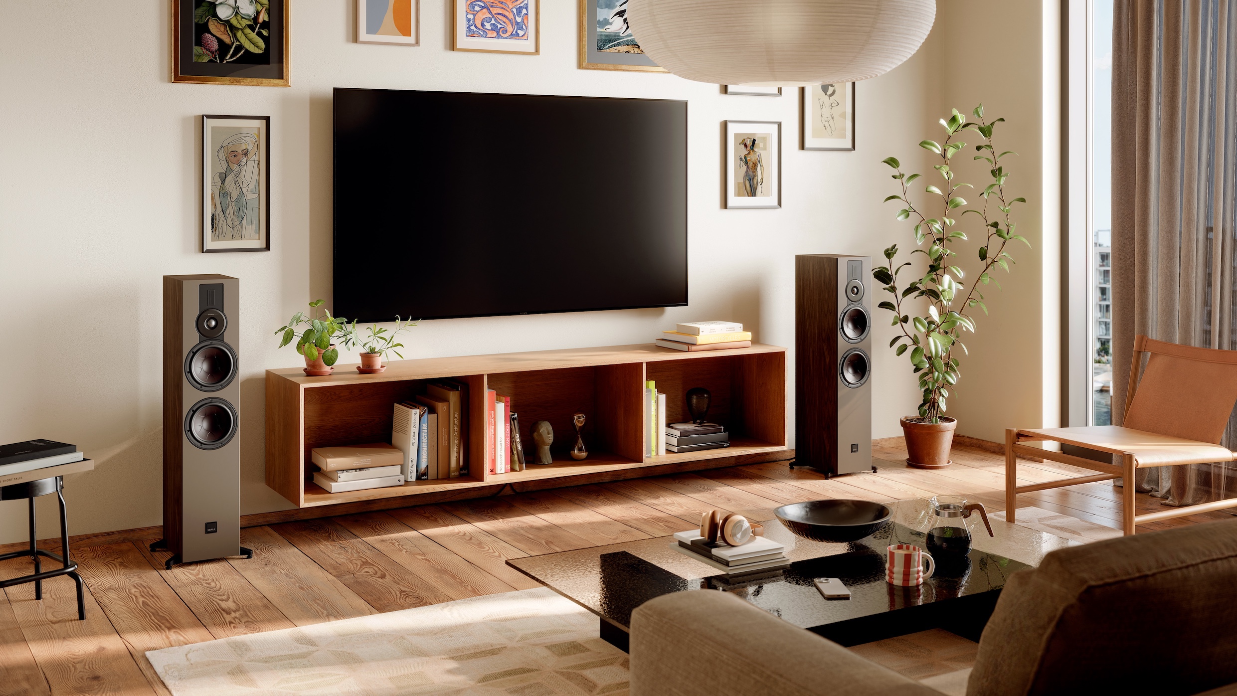 Two Dali Sonik floorstanding speakers either side of a wall-mounted TV and cabinet in a light and airy lounge.