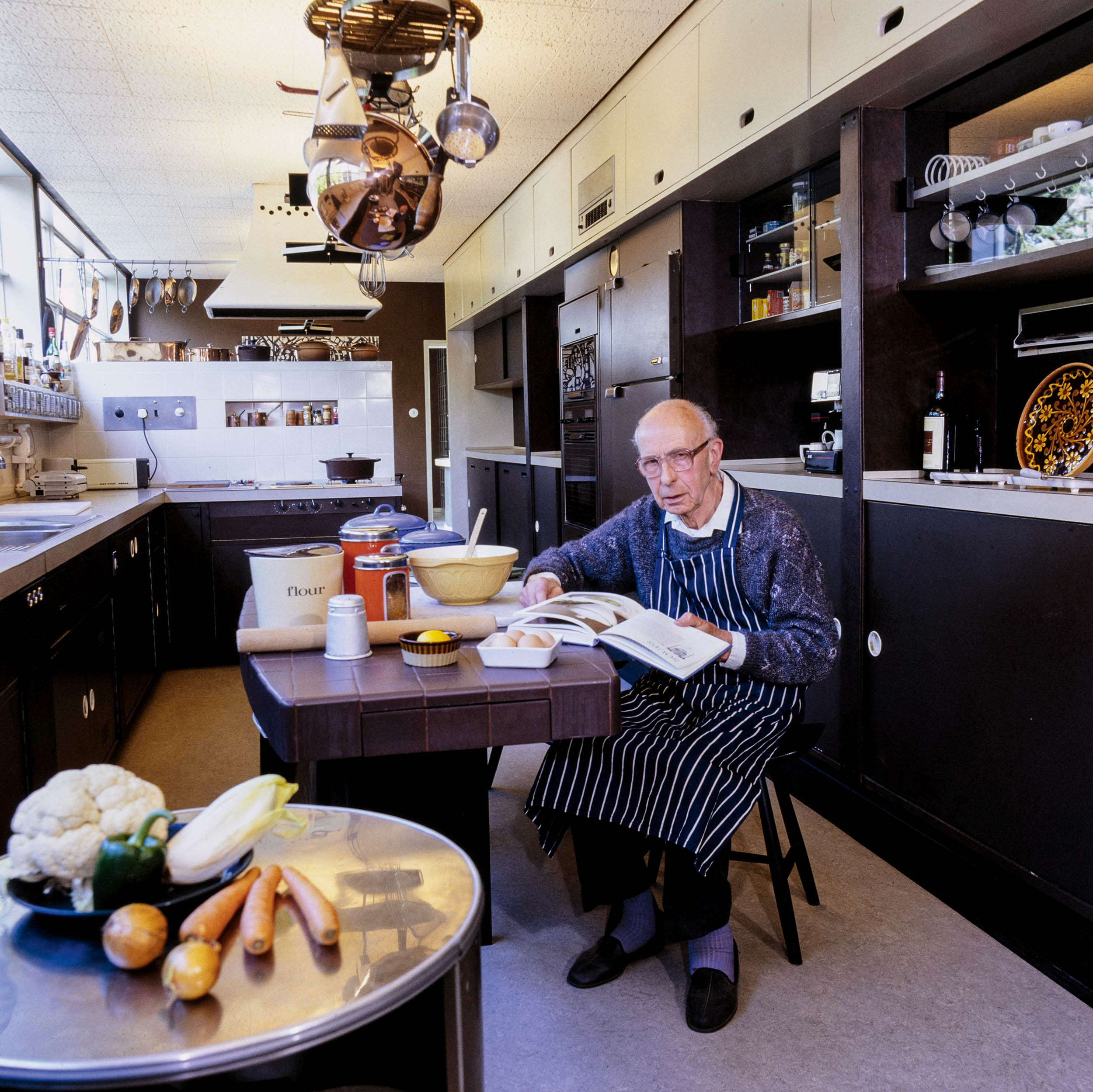 Man at table reading book and cooking
