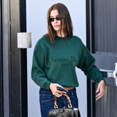a woman with brown hair in a green sweatshirt and blue jeans