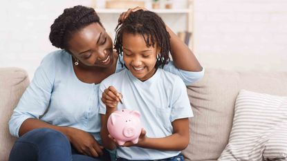 Mom with young daughter putting coin in piggybank