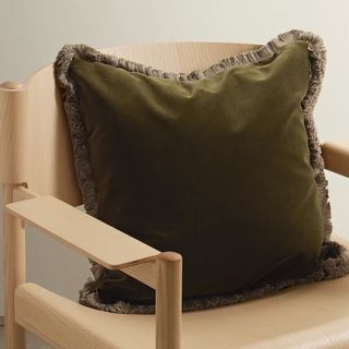 A large green velvet throw pillow with a cotton ruffle