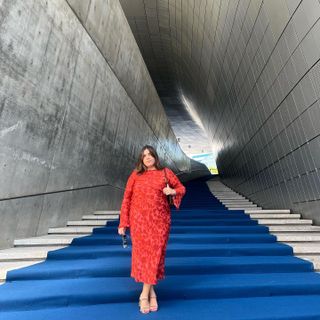 Woman at the TWA Hotel in a red floral maxi dress