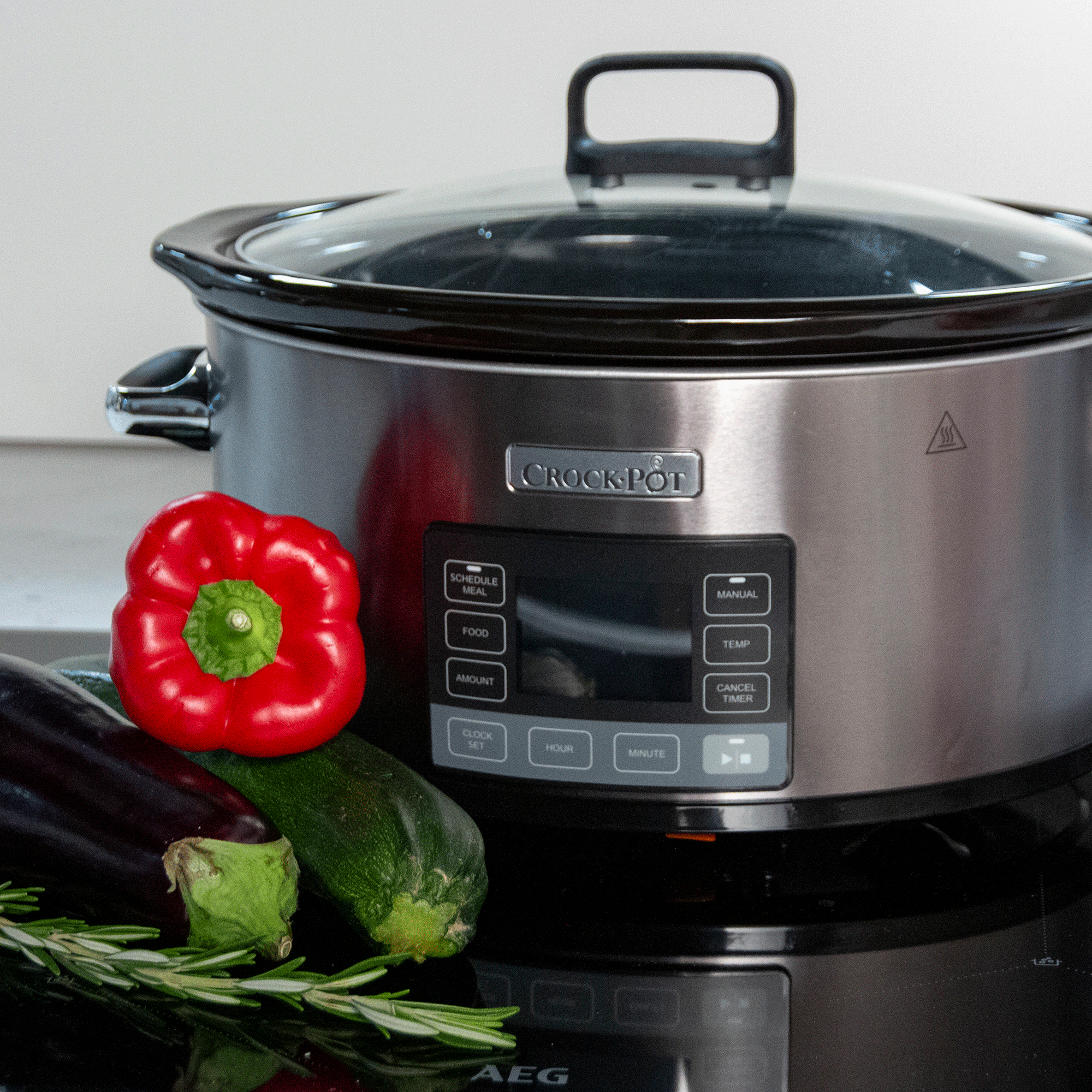 Silver slow cooker with vegetables on hob