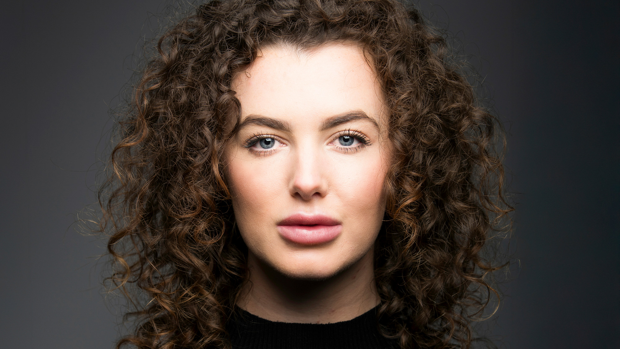 Close-up studio portrait of model by James Paterson on a dark grey background